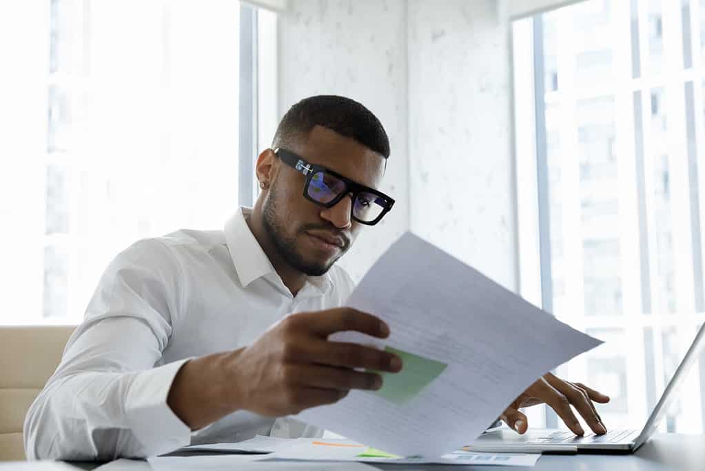 Man Wearing Glasses Looking at Free Corporate Travel Policy Template
